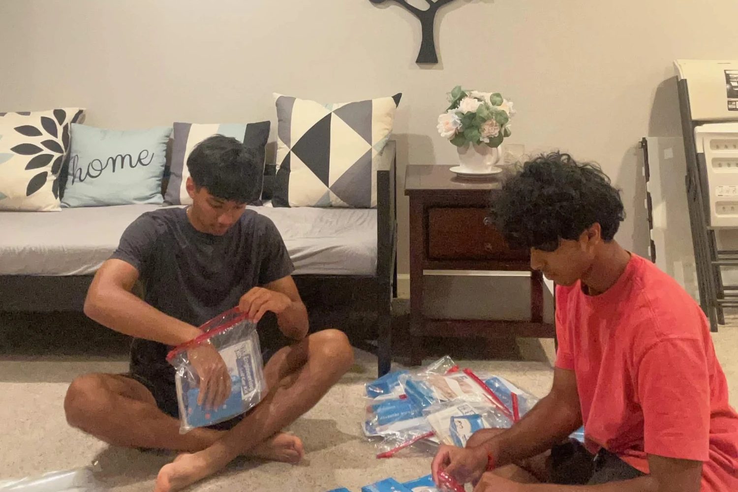 Two Future Spark students sitting on a living room floor packing kits
